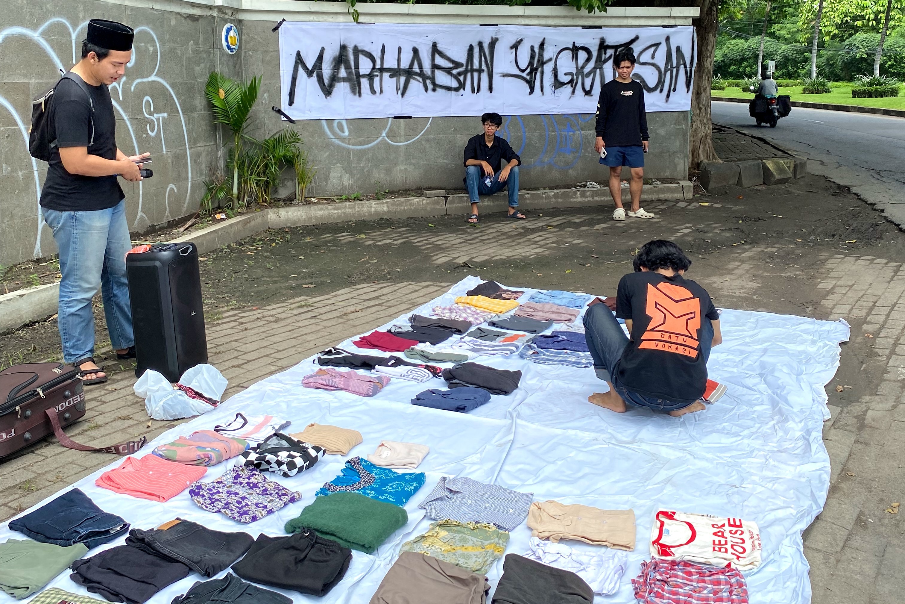 Gambar Anggota Tim Lapak Bebas Biaya Surabaya ketika menyusun pakaian yang akan dibagikan kepada masyarakat di kegiatan berbagi Marhaban Ya Gratisan di tepi Jalan Raya ITS