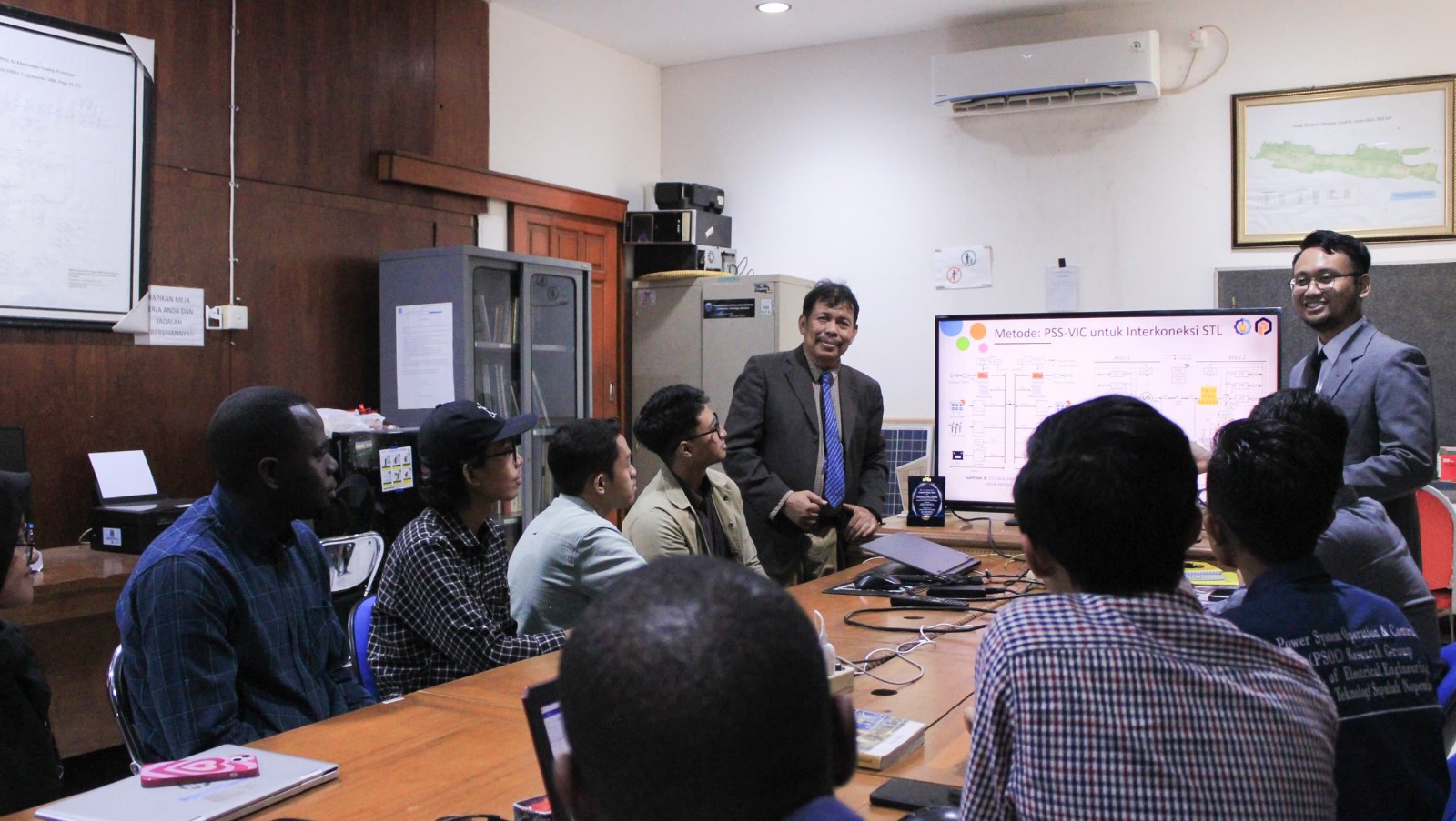 Gambar Dr Mohamad Almas Prakasa ST MT (berdiri kanan) dan tim peneliti Operasi dan Pengendalian Sistem Tenaga (PSOC) saat bimbingan dengan Prof Dr Ir Imam Robandi (berdiri kiri)