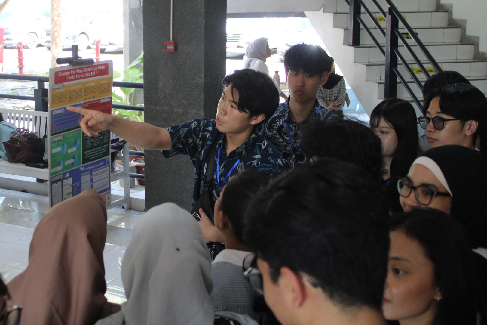 Salah satu mahasiswa dari Shibaura Institute of Technology (SIT) saat menjelaskan poster mengenai mengubah cara berkendara dengan kendaraan motor listrik di Surabaya