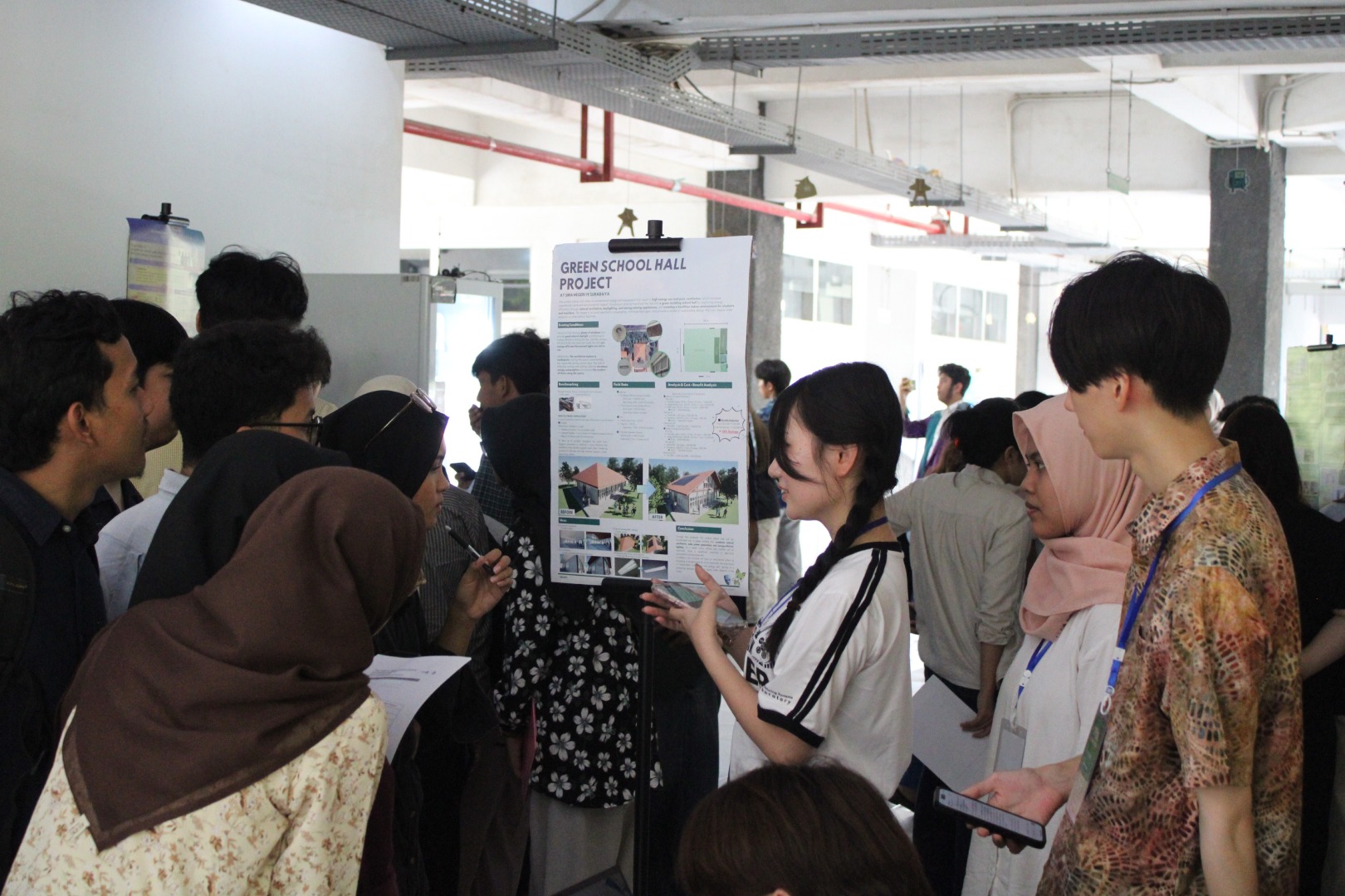 Salah satu mahasiswa dari Shibaura Institute of Technology (SIT) saat menjelaskan poster mengenai optimalisasi bangunan SMA 19 Surabaya dalam program GPbL