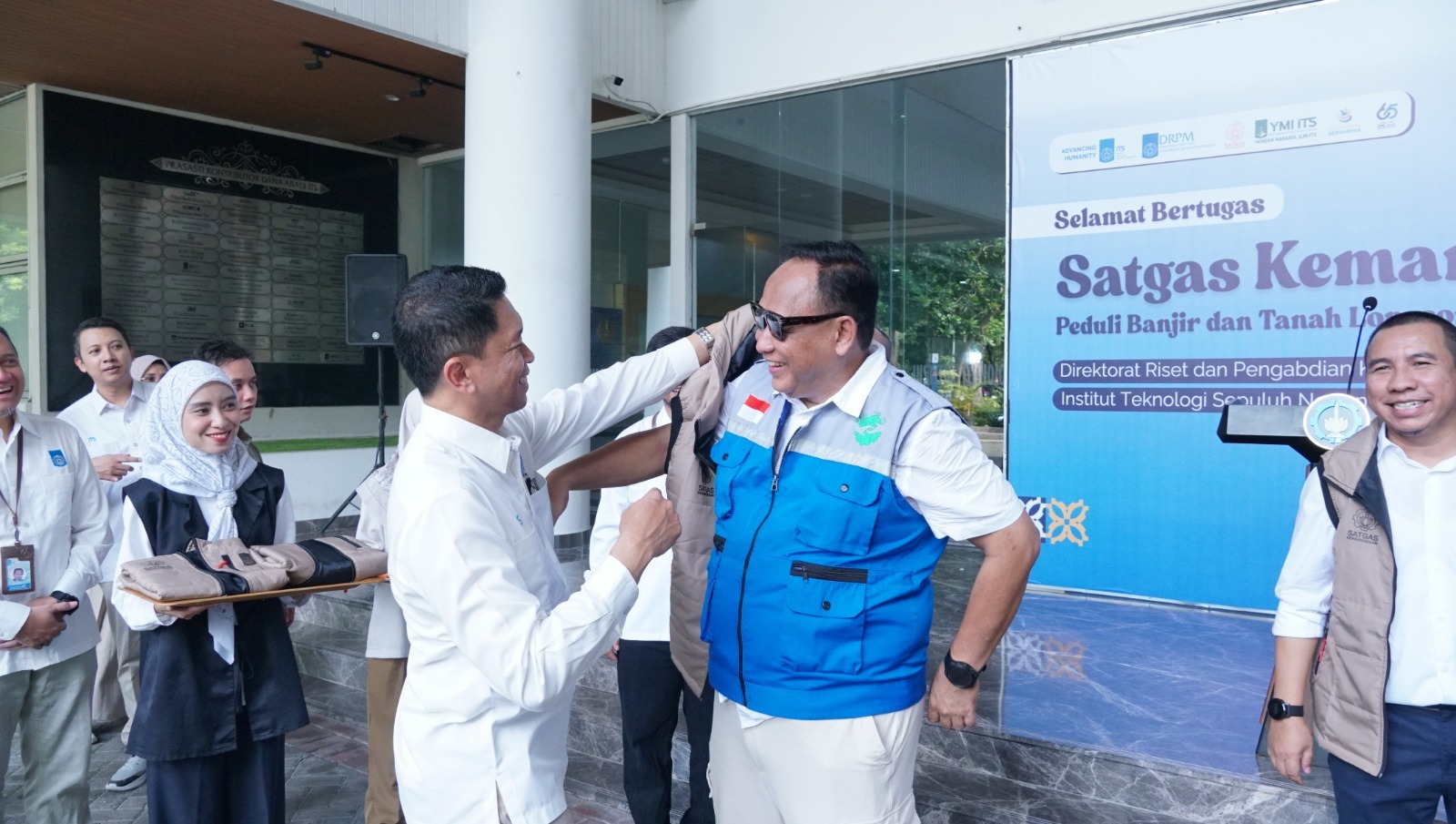 Penyematan rompi sebagai simbol pelepasan Satgas Kemanusiaan ITS oleh Rektor ITS Prof Ir Bambang Pramujati ST MSc Eng PhD kepada Ketua YMI ITS Ir Triyanto