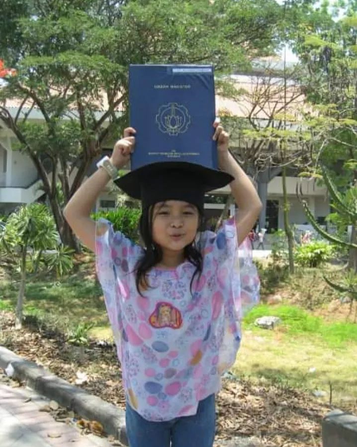 Nadhifa Laudza Shabrina (saat berusia 10 tahun) memegang ijazah almarhum ayahnya yang telah diwisuda di depan gedung Graha Sepuluh Nopember ITS pada Oktober 2009 silam