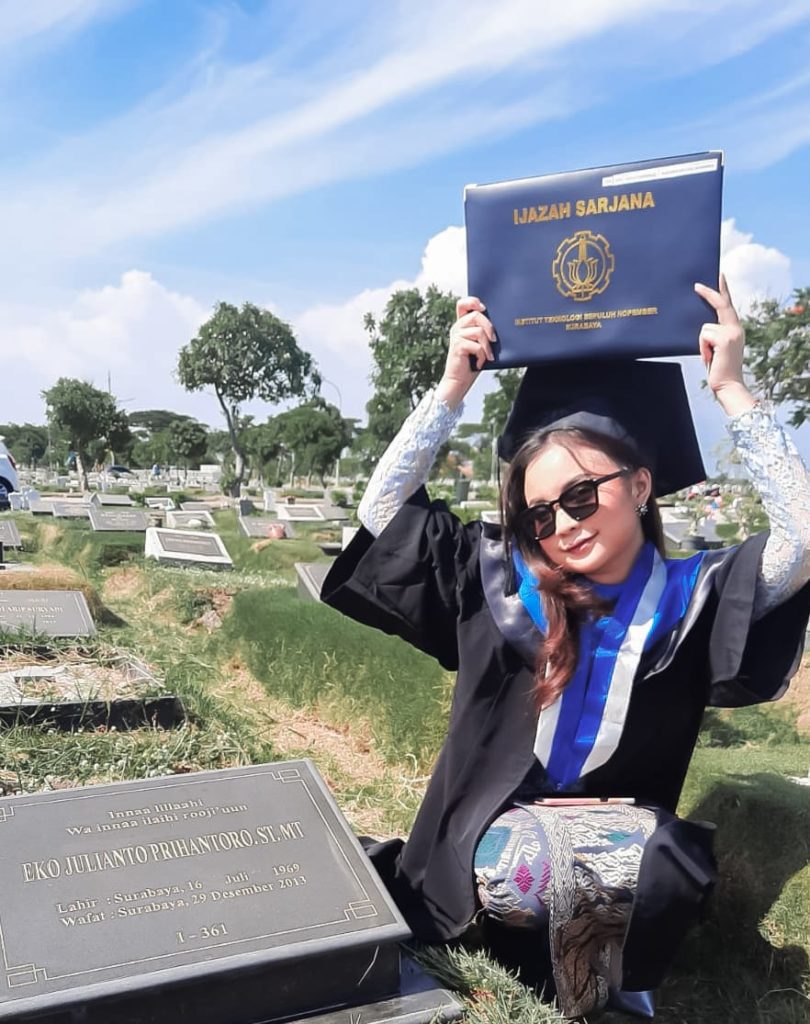 Nadhifa Laudza Shabrina yang berpose seperti potret masa kecilnya ketika memegang ijazah sang ayah saat berziarah ke makam usai diwisuda di ITS