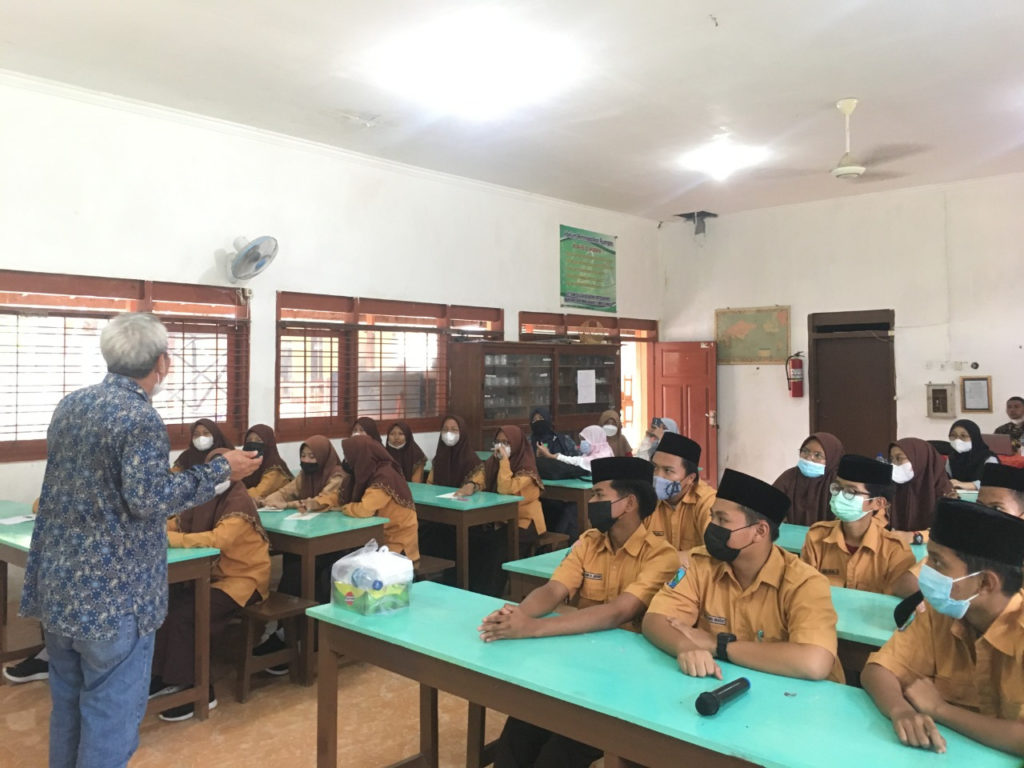 Dr Drs Mochamad Zainuri MSi (berdiri) saat memberikan penjelasan kepada para siswa mengenai cara pembuatan dan prinsip kerja alat serta cara merawat media filter air dari batok kelapa