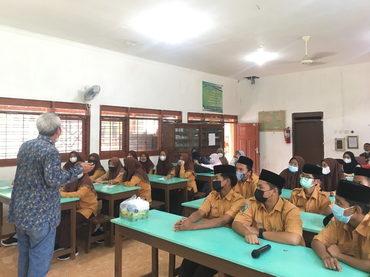 Dr Drs Mochamad Zainuri MSi (berdiri) saat memberikan penjelasan kepada para siswa mengenai cara pembuatan dan prinsip kerja alat serta cara merawat media filter air dari batok kelapa