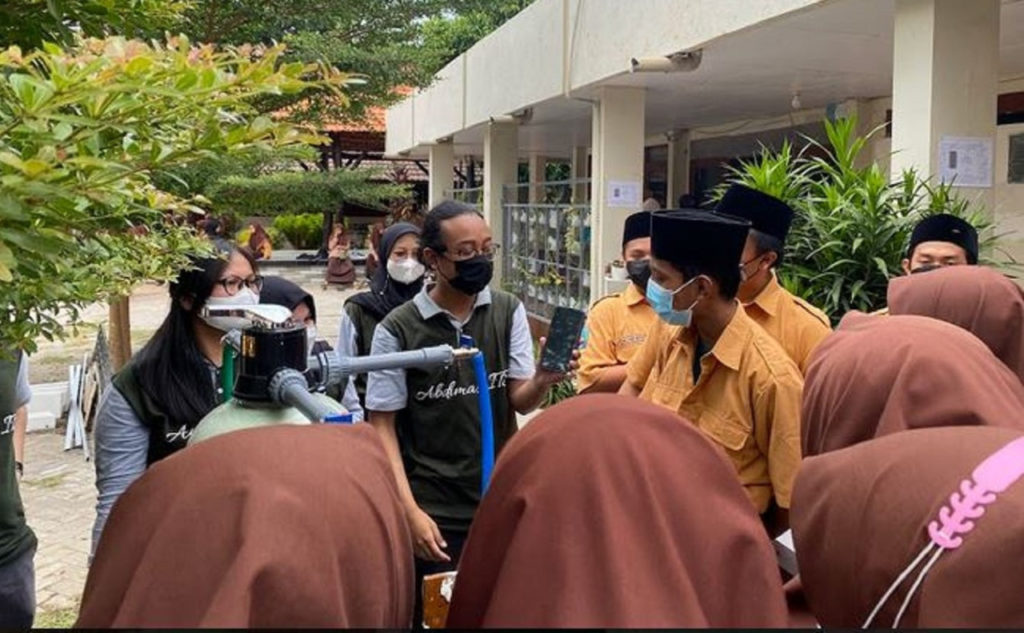 The ITS Physics Department KKN Abmas team shows how the water filter from coconut shell charcoal works to the students of SMA A Wahid Hasyim Tebuireng, Jombang.