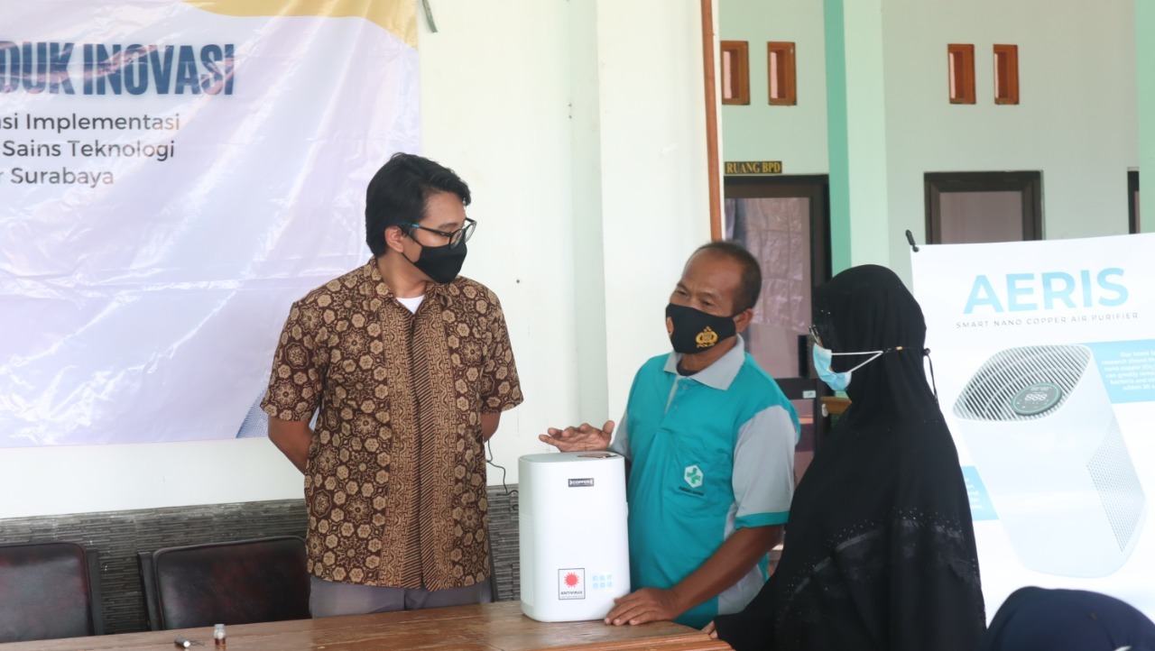 Salah satu mahasiswa Departemen Teknik Material dan Metalurgi ITS, Ahmad Fahmi Prakoso (kiri) menjelaskan cara penggunaan air purifier kepada masyarakat