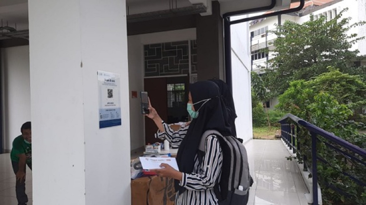 Mahasiswi Departemen Teknik Geofisika ITS saat melakukan scan PeduliLindungi sebelum masuk kelas PTM