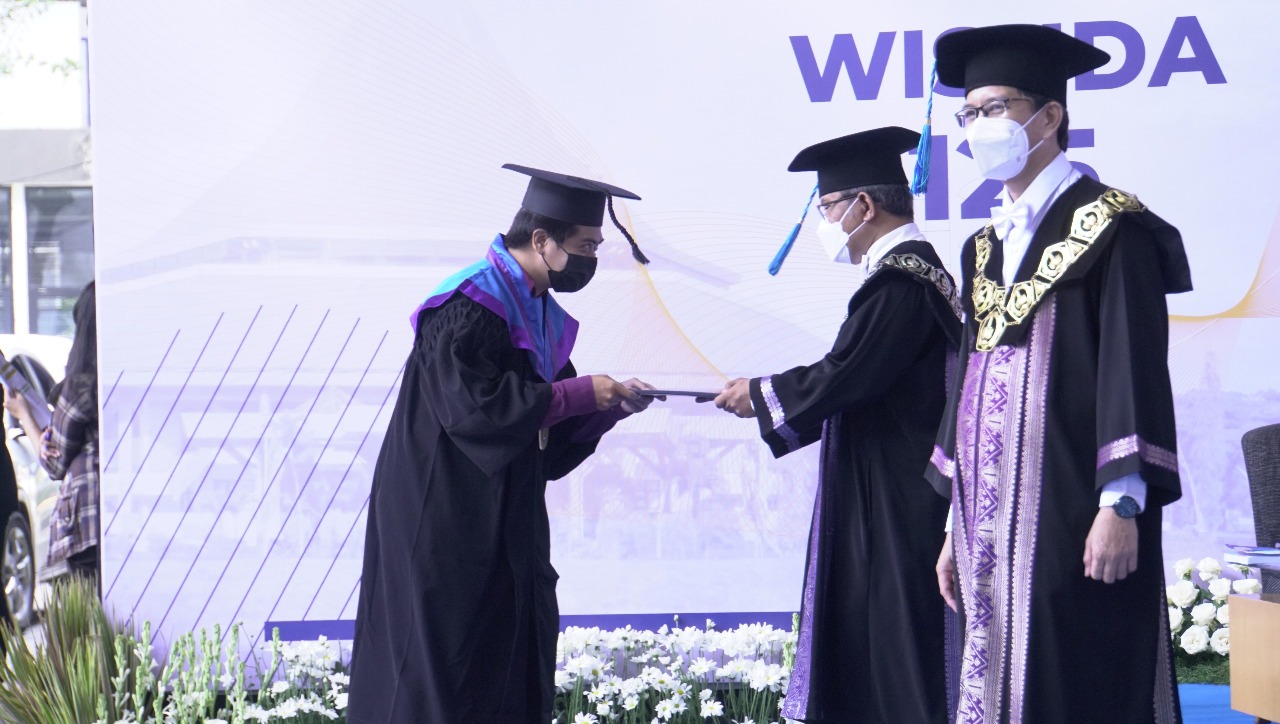 Salah satu wisudawan yang mengikuti prosesi secara drive thru di Wisuda ke-125 ITS saat menerima ijazah dari dekan lebih dulu