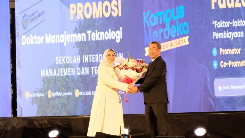 Muhammad Fauzan (kanan) menerima karangan bunga dari sang istri Niluh Putu Dewi Kartikasari SE MBA usai dinyatakan lulus sebagai doktor dari SIMT ITS