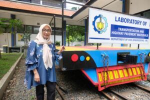 Prof Ir Hera Widyastuti MT PhD tengah menunjukkan imitasi rel kereta api yang berasal dari Laboratorium Transportasi dan Material Perkerasan Teknik Sipil ITS