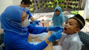 Gambar kegiatan pemeriksaan gigi anak-anak oleh dokter dari alumni FKG Unair dalam kegiatan Edukasi dan Skrining Kesehatan Gigi dan Mulut