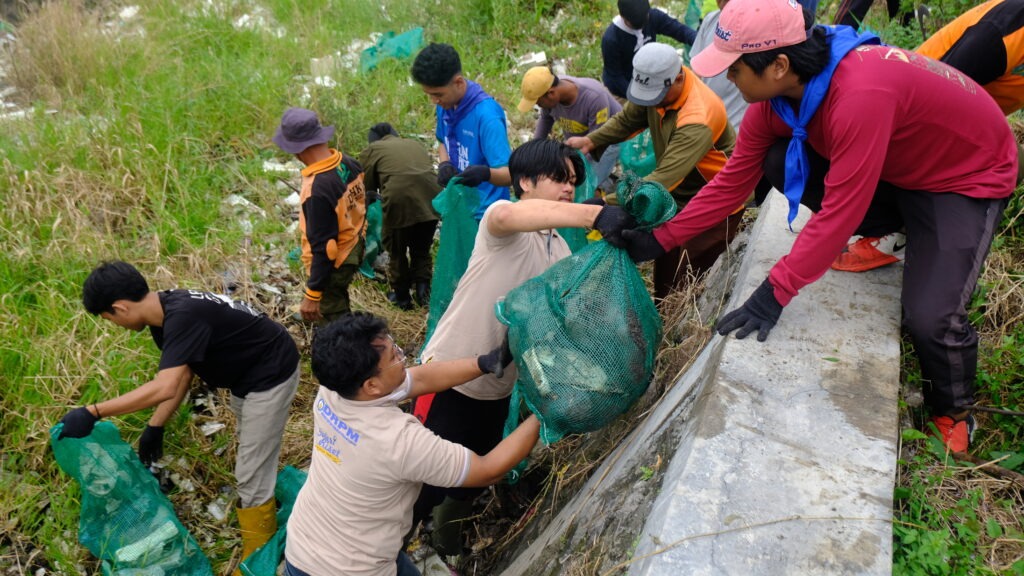 Mahasiswa ITS (berbaju coklat) bekerja sama dengan masyarakat sekitar saat turun langsung membersihkan sungai