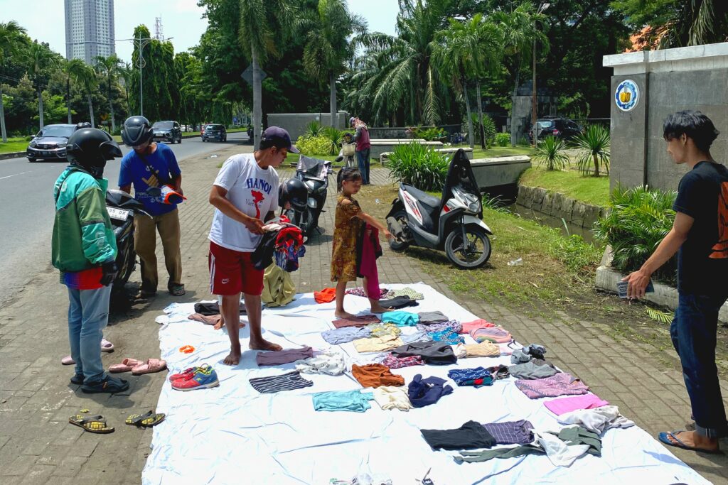 Gambar Berbagai jenis pakaian mulai dari baju, celana, rok, hingga sepatu yang disediakan oleh Lapak Bebas Biaya Surabaya untuk dibagikan kepada masyarakat secara cuma-cuma