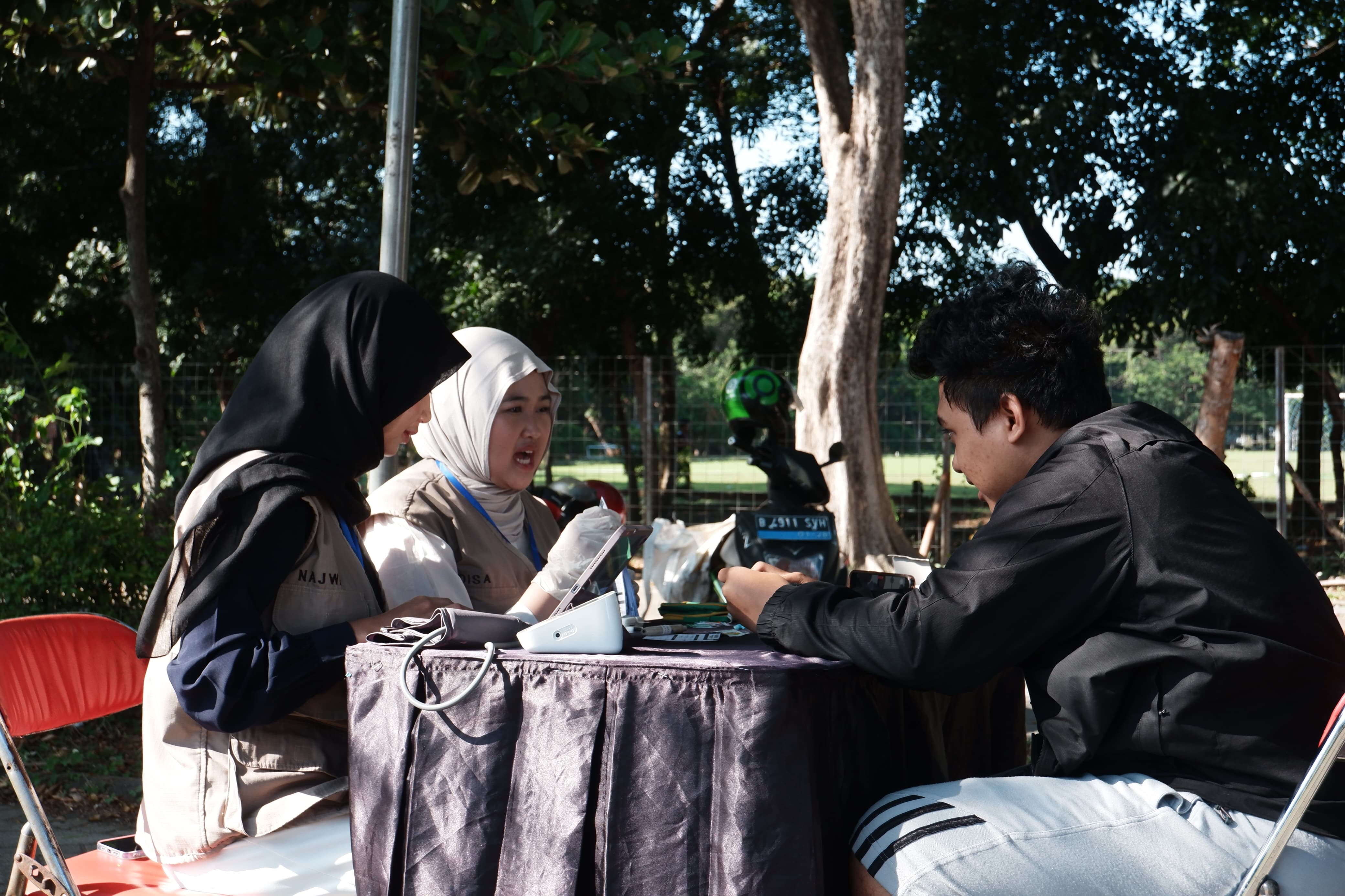 Gambar Mahasiswa FK UNAIR ketika melakukan medical check up terhadap pengunjung layanan servis sepeda motor gratis LBMM ITS