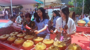 Salah satu siswa SMP YPPI 1 Surabaya (tengah) saat menunjukkan cara bermain gamelan kepada para peserta CommTECH Camp 2026