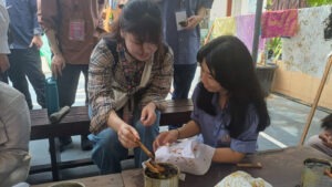 Siswa SMP YPPI 1 Surabaya (kanan) saat mengajarkan cara mencanting batik kepada salah satu delegasi CommTECH Camp 2026 asal Jepang