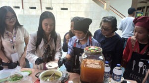 Siswa SMP YPPI 1 Surabaya (tengah) saat mendemonstrasikan cara pembuatan minuman tradisional sinom kepada para peserta CommTECH Camp 2026