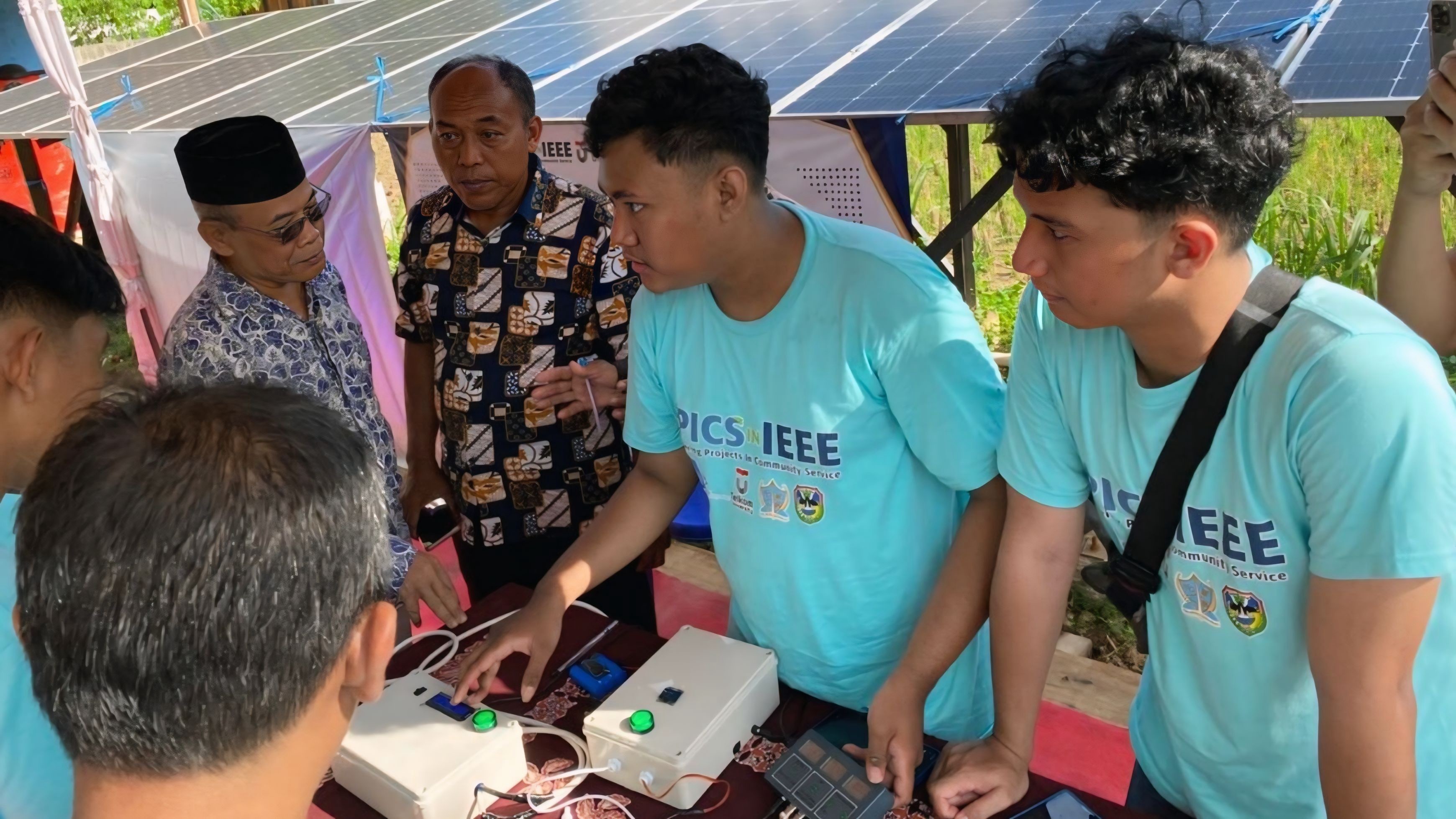 Tim EPICS in IEEE 2026 ITS menjelaskan cara kerja sistem penyediaan air berbasis panel surya terintegrasi Internet of Things (IoT) kepada warga di Desa Cokrokembang, Pacitan