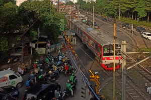 Sejumlah pengendara sepeda motor dan mobil berhenti saat kereta komuter melintas di perlintasan sebidang (sumber: Suara Merdeka)