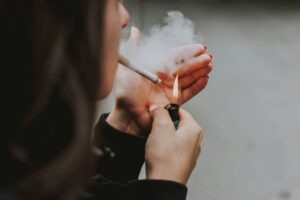 Gambar Seseorang perempuan menyulut rokok (sumber: unsplash)