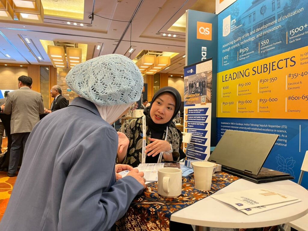 Salah satu staf dari Direktorat Kemitraan Global (DKG) ITS mempromosikan kampus ITS kepada salah satu pengunjung QS EduData Summit 2026 di Singapura