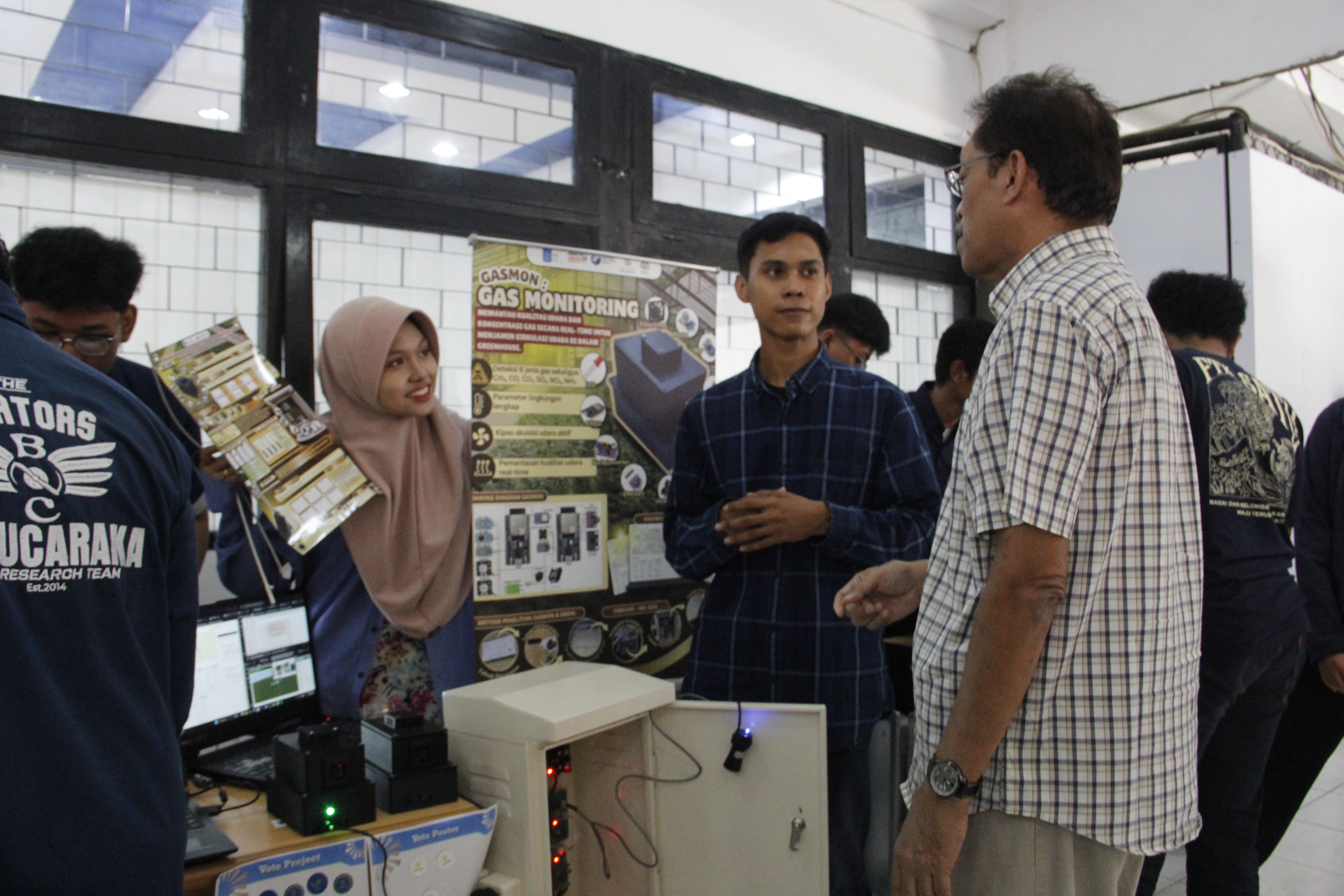 Gambar (dua dari kanan) Project Manager PjBL 4-09 Septian Kevin Ma’arif menjelaskan tentang inovasinya kepada pengunjung pameran.