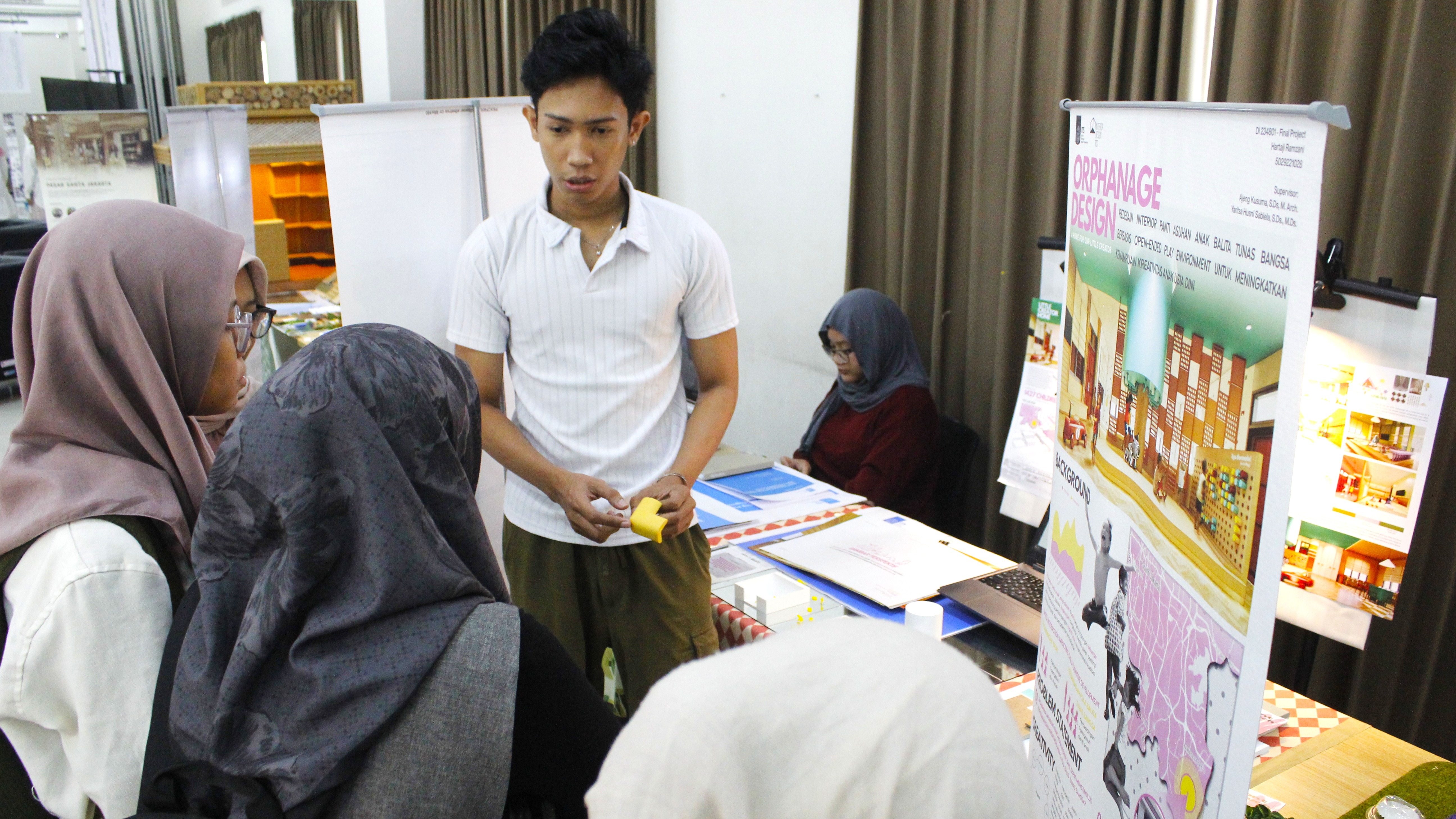 Salah satu mahasiswa Departemen Desain Interior ITS saat memamerkan karya Tugas Akhir (TA)-nya di hadapan pengunjung