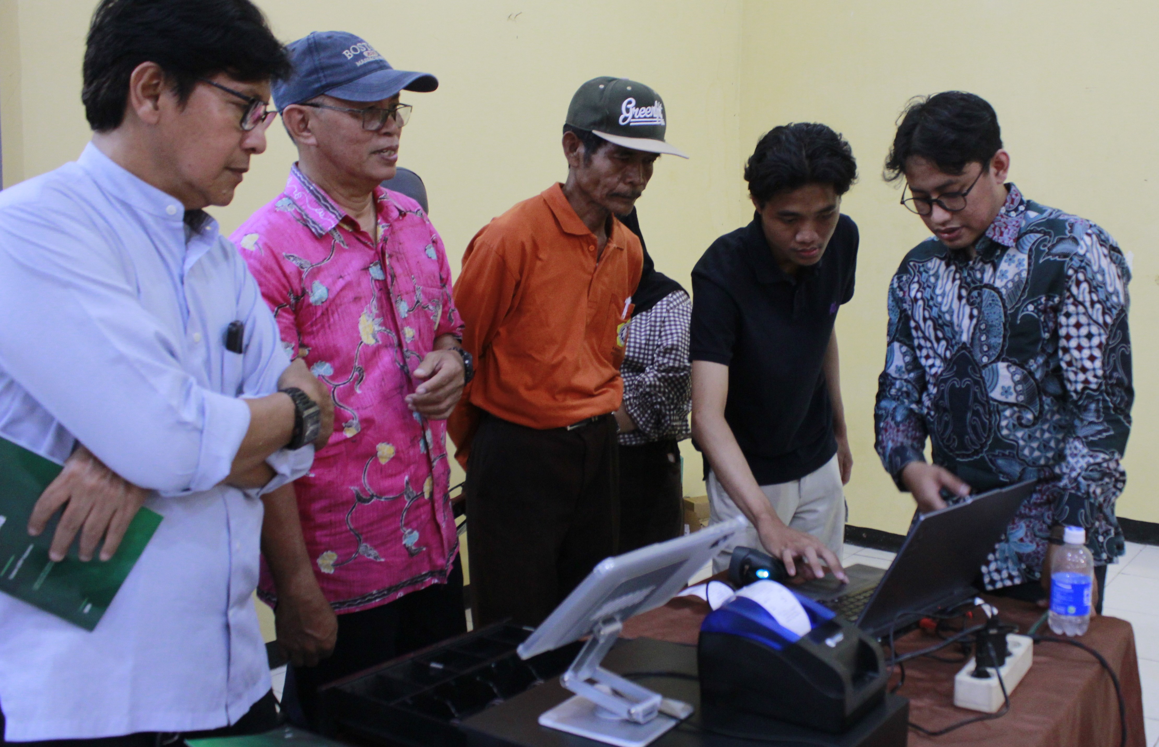 Gambar tim pengabdian masyarakat (abmas) Departemen Teknik Informatika ITS (dua dari kanan) mendemonstrasikan penggunaan CerdasERP Koperasi kepada pengurus Koperasi Kelurahan Merah Putih.