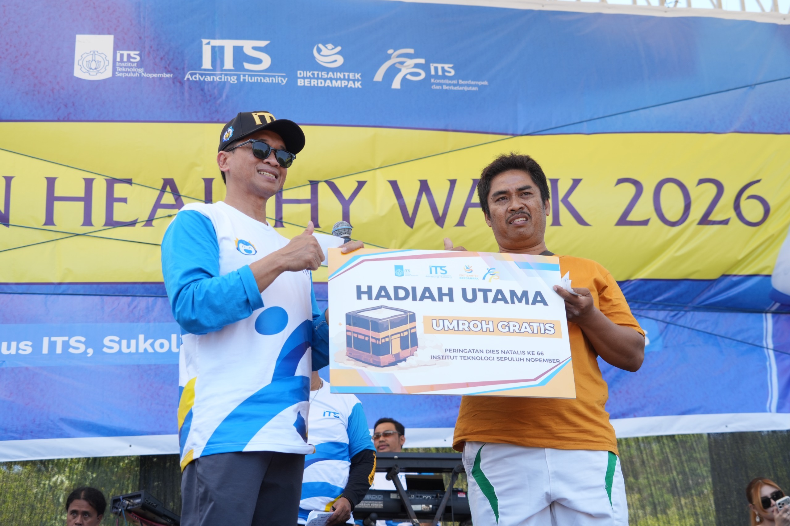 (kiri) Prof Bambang Pramujati serahkan hadiah utama ITS FUN HEALTHY WALK 2026 berupa tiket Umroh kepada salah satu peserta terpilih