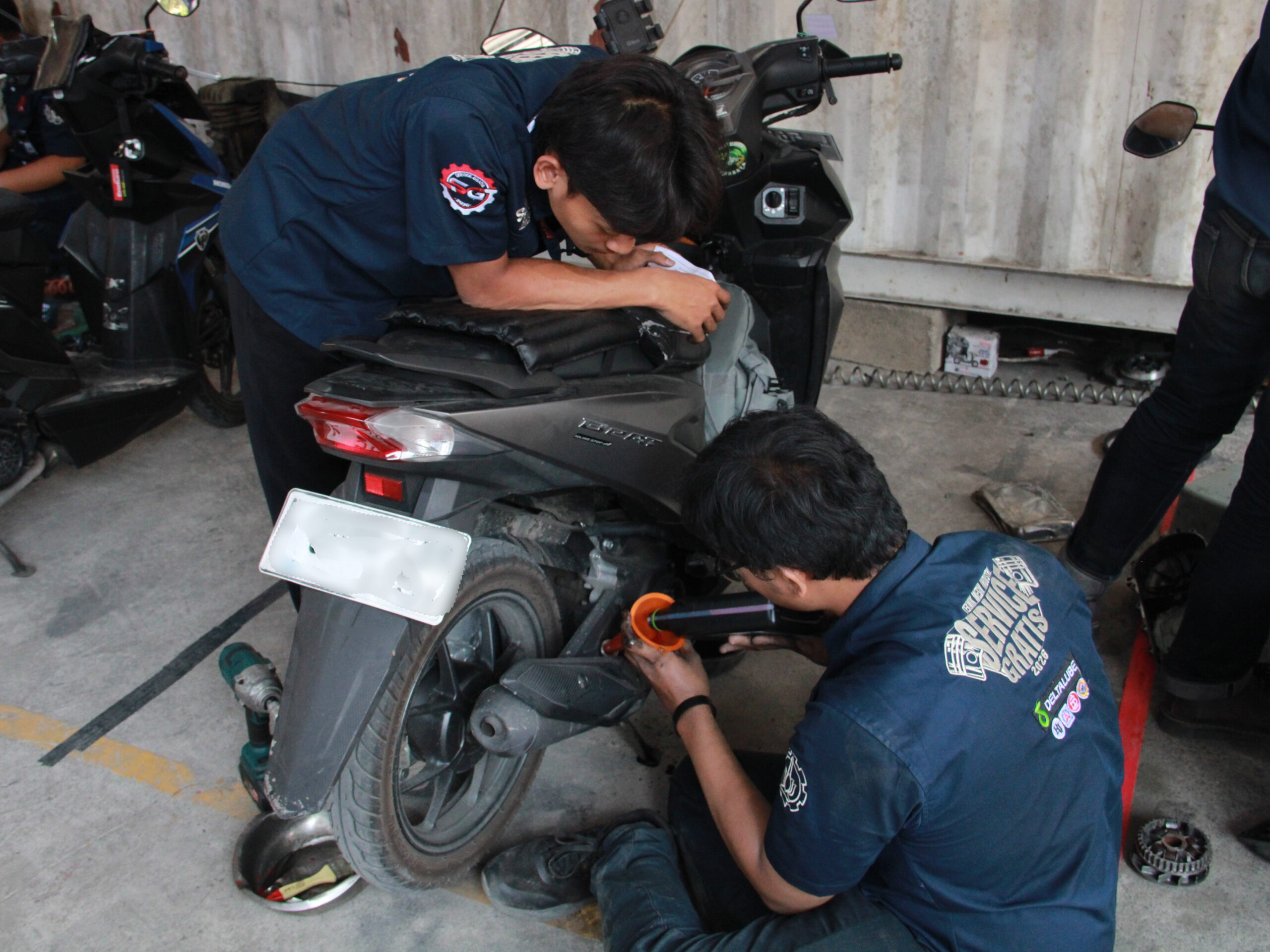 Mahasiswa Departemen Teknik Mesin Industri ITS saat melakukan penggantian oli pada kegiatan Servis Gratis DTMI ITS 2026