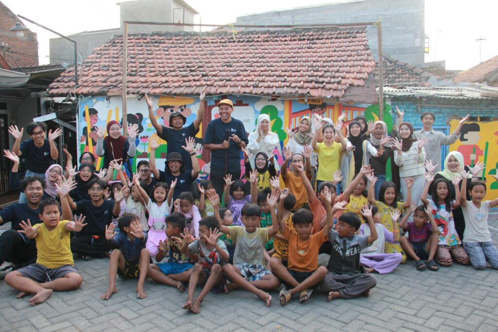 Tim abmas ITS bersama komunitas dan penggiat Kampoeng Dolanan Surabaya berpose di depan mural hasil revitalisasi