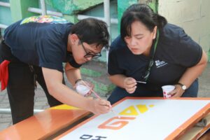 Anggota tim abmas Yosia Enggar Kurniawan SDs MSn (kiri) dan Dr Senja Aprela Agustin ST MDs (kanan) saat melakukan pengecatan signage Kampoeng Dolanan