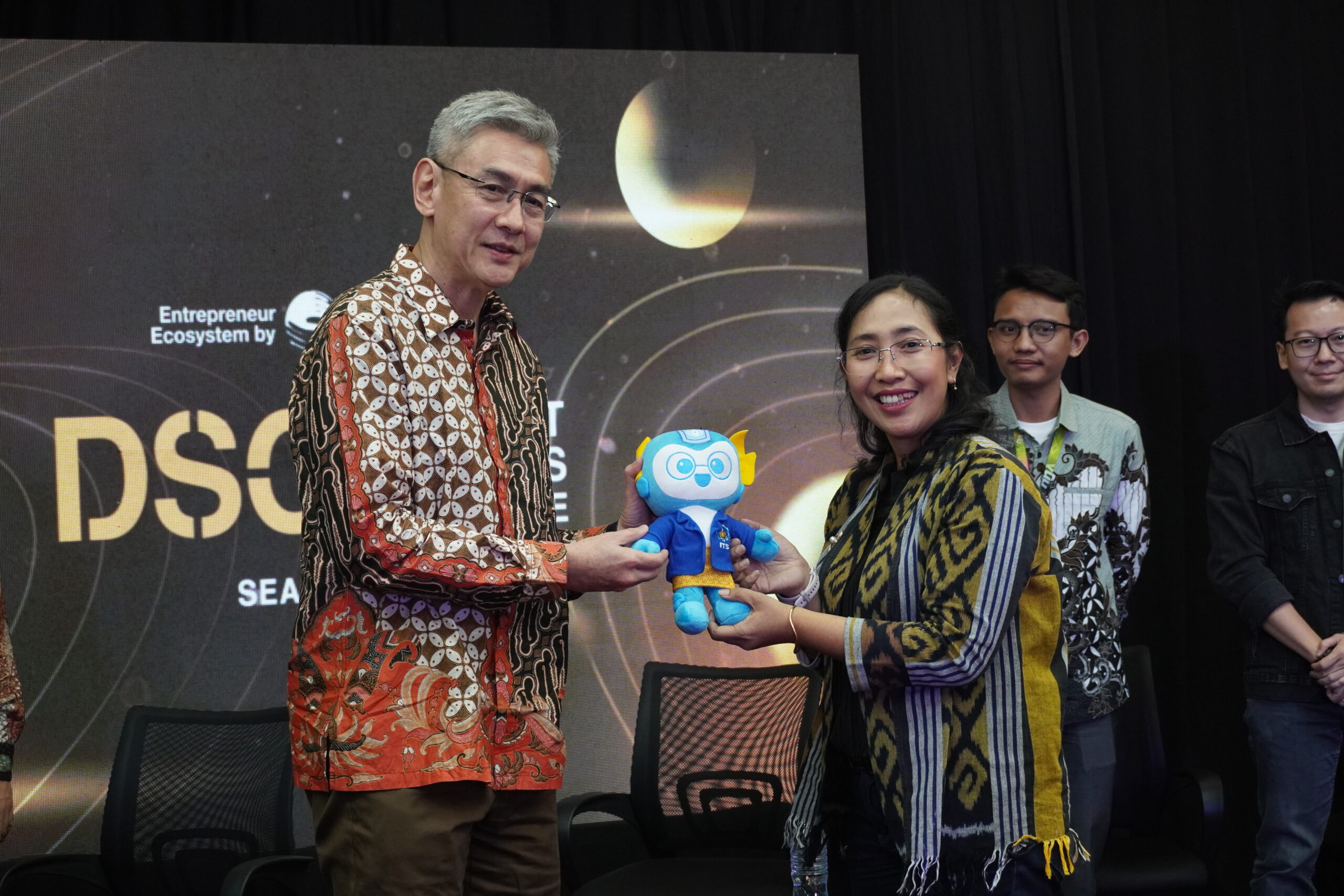 Chairman of the DSC Board of Commissioners Surjanto Yasaputera (left) hands over a mascot to a representative of ITS as a token of appreciation, accompanied by other event delegates at the Science Techno Park ITS.